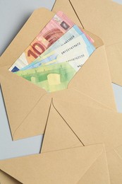 Photo of Money bonus. Envelopes with euro banknotes on light grey background, flat lay