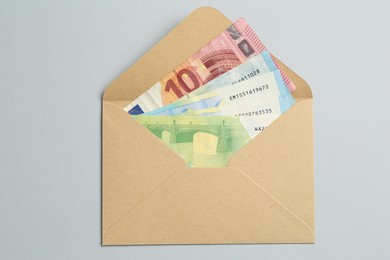 Photo of Money bonus. Envelope with euro banknotes on light grey background, top view