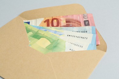 Photo of Money bonus. Envelope with euro banknotes on light grey background, closeup