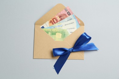 Photo of Money bonus. Envelope with euro banknotes on light grey background, top view