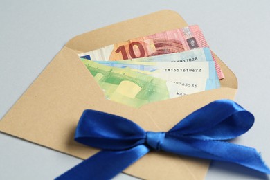 Photo of Money bonus. Envelope with euro banknotes on light grey background, closeup