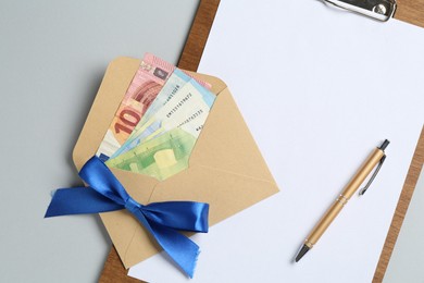 Photo of Money bonus. Envelope with euro banknotes and clipboard on light grey background, top view