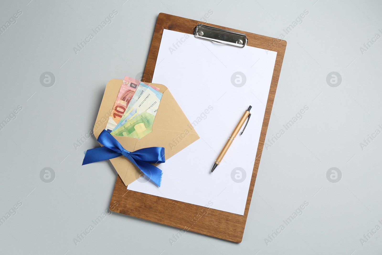 Money bonus. Envelope with euro banknotes and clipboard on light grey background, top view Photo of Money bonus. Envelope with euro banknotes and clipboard on light grey background, top view