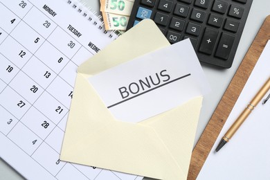 Photo of Card with word Bonus, money, calendar and calculator on light grey background, flat lay