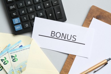Photo of Card with word Bonus, money, clipboard and calculator on light grey background, flat lay