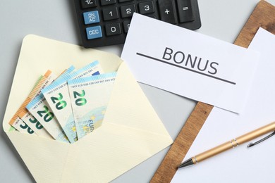 Photo of Card with word Bonus, money, clipboard and calculator on light grey background, flat lay