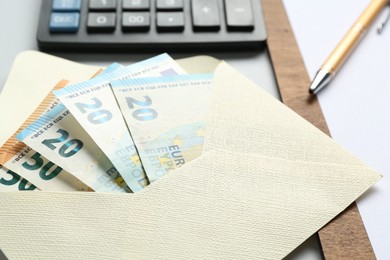 Photo of Money bonus. Envelope with euro banknotes on light grey background, closeup