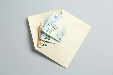 Photo of Money bonus. Envelope with euro banknotes on light grey background, top view