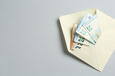 Photo of Money bonus. Envelope with euro banknotes on light grey background, top view. Space for text