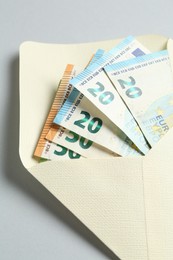 Photo of Money bonus. Envelope with euro banknotes on light grey background, closeup