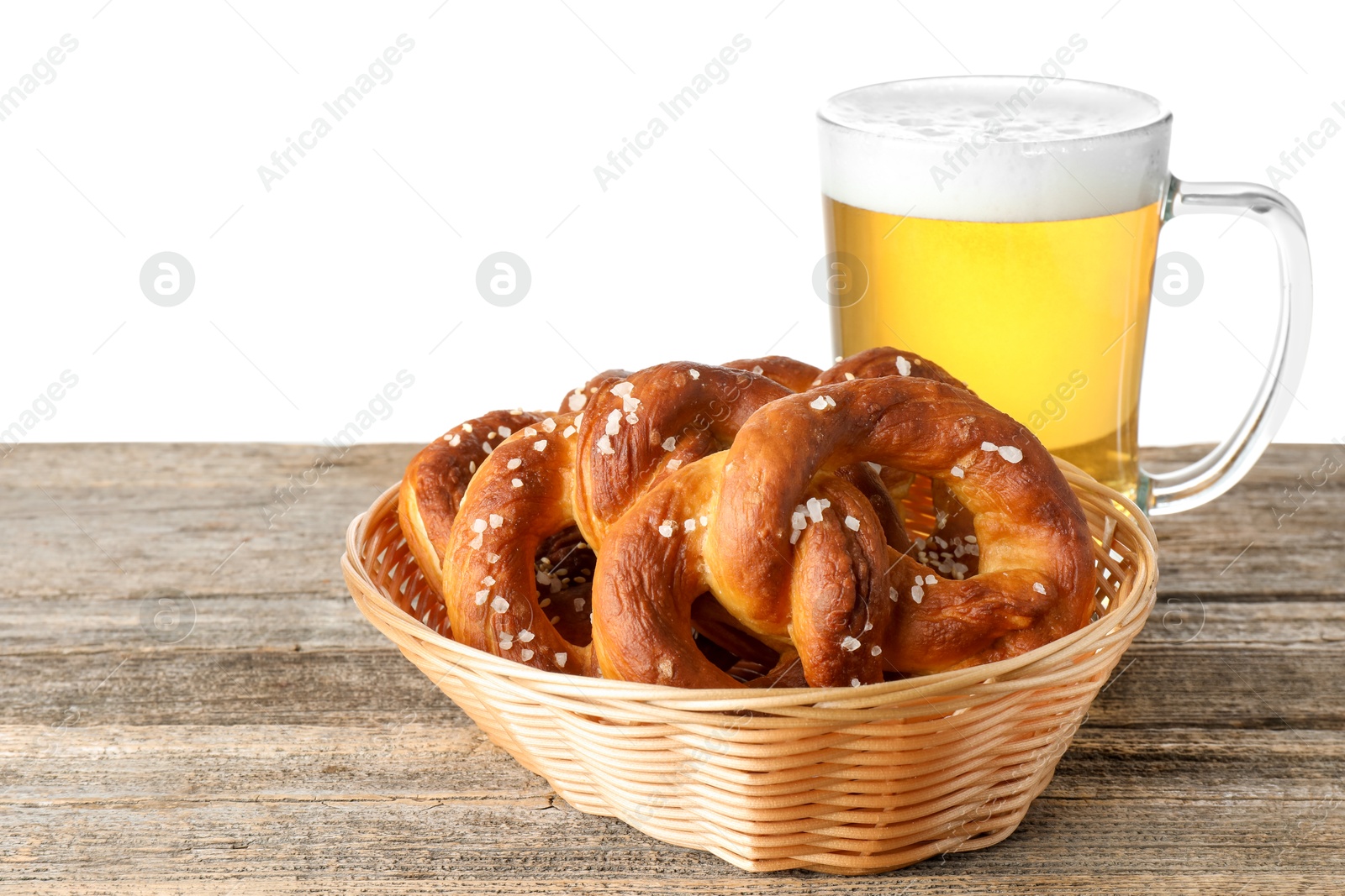 Photo of Tasty pretzels and glass of beer on wooden table against white background