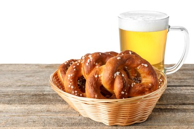 Photo of Tasty pretzels and glass of beer on wooden table against white background
