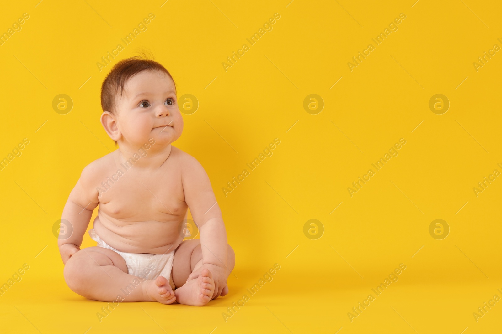 Cute little baby in diaper sitting on yellow background. Space for text Photo of Cute little baby in diaper sitting on yellow background. Space for text