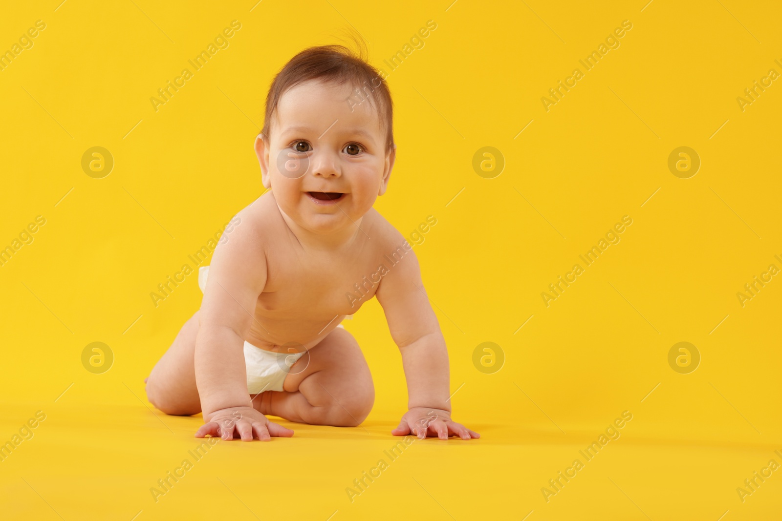 Cute little baby crawling on yellow background Photo of Cute little baby crawling on yellow background