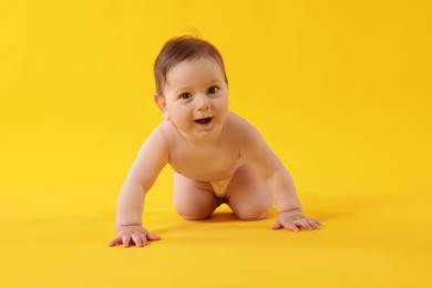 Photo of Cute little baby crawling on yellow background