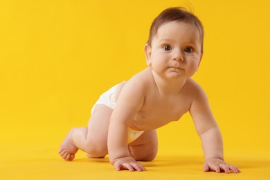 Photo of Cute little baby crawling on yellow background