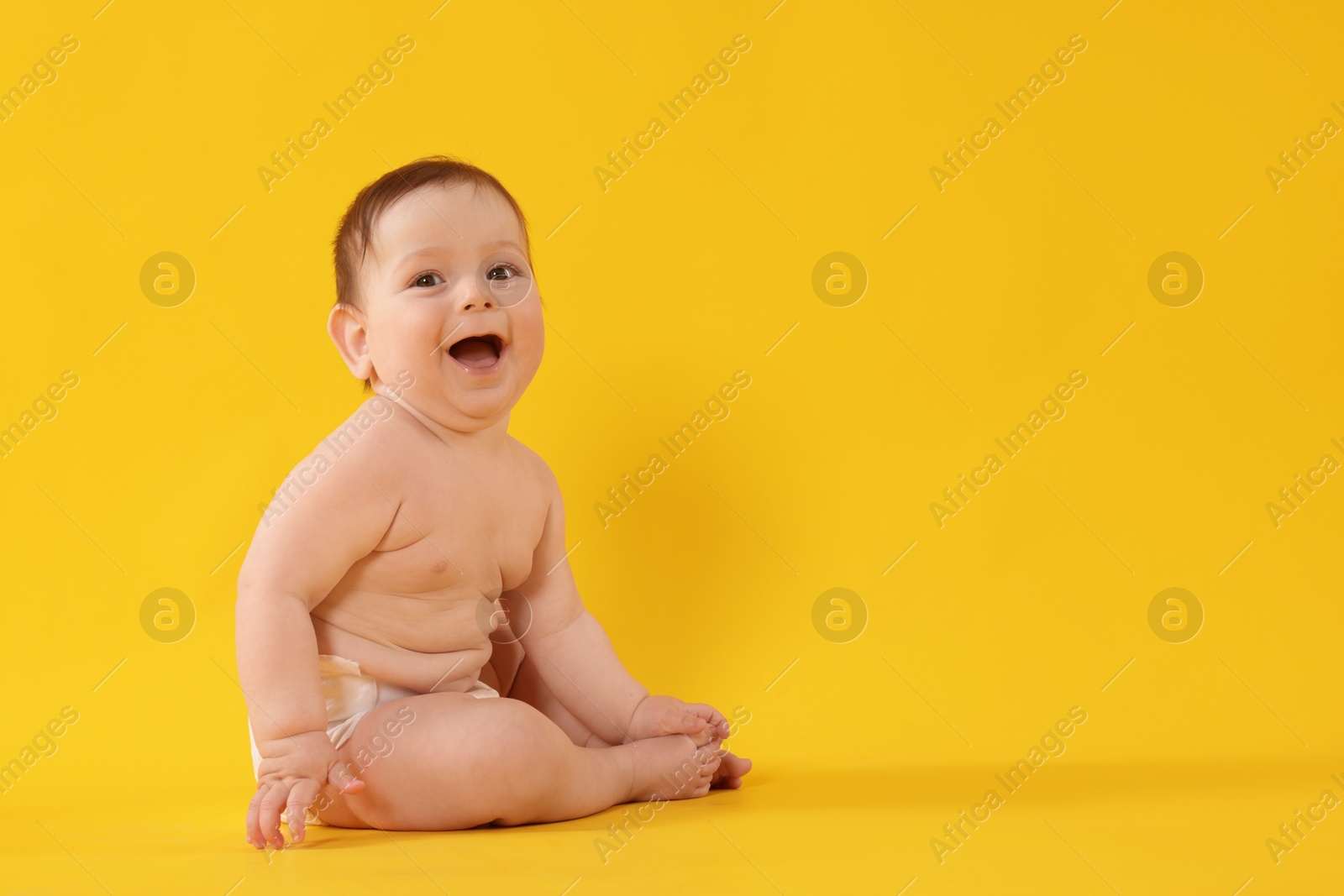Cute little baby in diaper sitting on yellow background. Space for text Photo of Cute little baby in diaper sitting on yellow background. Space for text