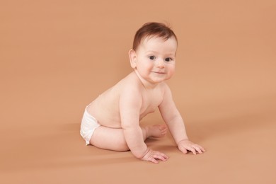 Photo of Cute little baby crawling on beige background