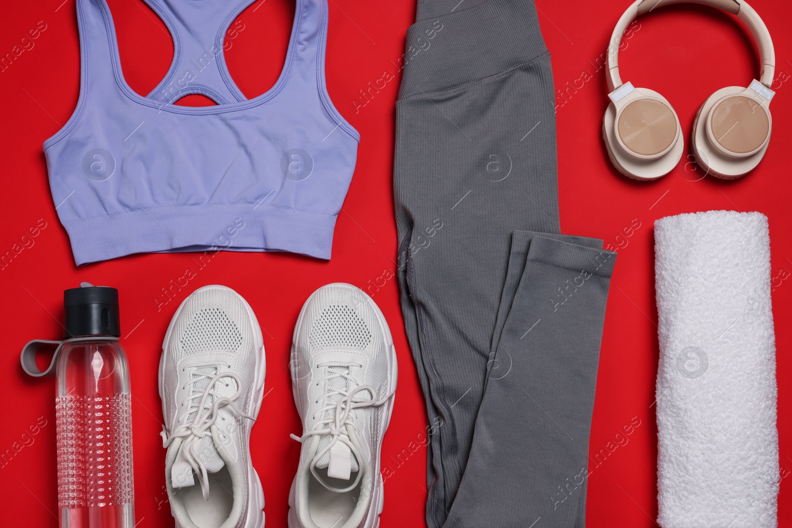 Sportswear, sneakers, towel, headphones and water bottle on red background, flat lay Photo of Sportswear, sneakers, towel, headphones and water bottle on red background, flat lay