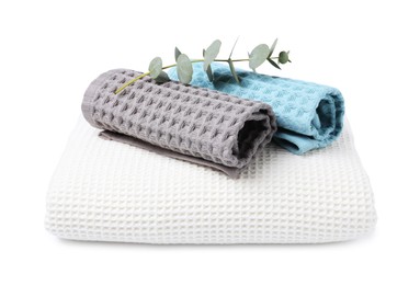 Photo of Clean waffle towels and eucalyptus branch isolated on white