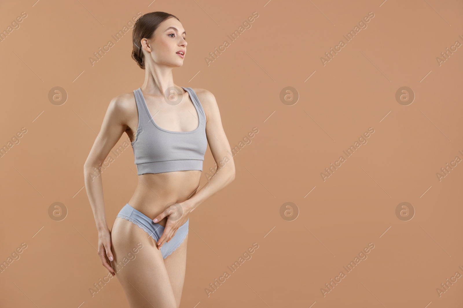 Woman wearing beautiful underwear on dark beige background, space for text Photo of Woman wearing beautiful underwear on dark beige background, space for text