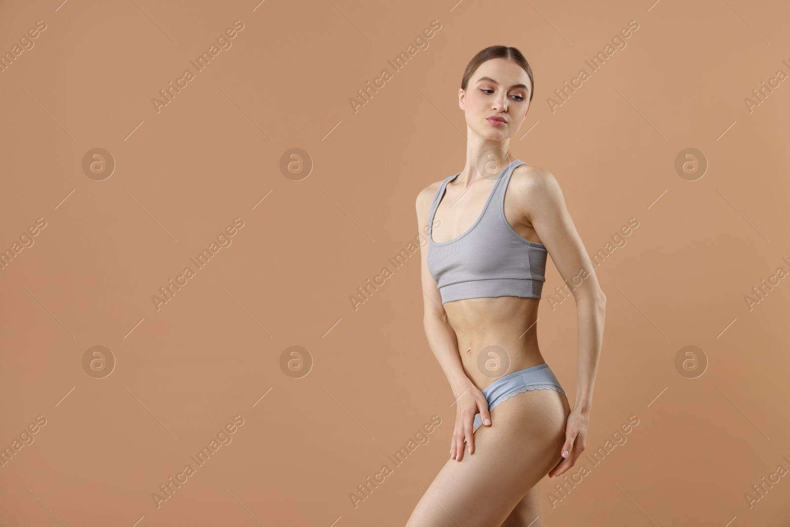 Woman wearing beautiful underwear on dark beige background, space for text Photo of Woman wearing beautiful underwear on dark beige background, space for text