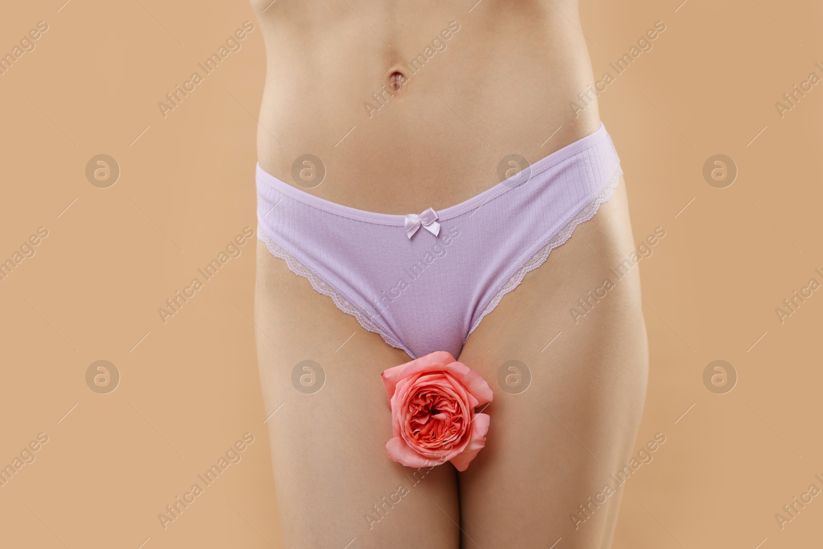 Woman with flower wearing beautiful underwear on beige background, closeup Photo of Woman with flower wearing beautiful underwear on beige background, closeup