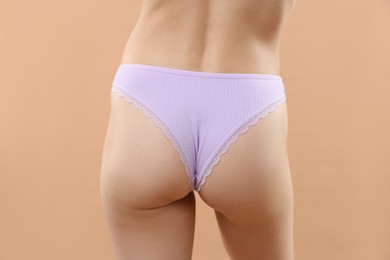 Photo of Woman wearing beautiful underwear on beige background, closeup