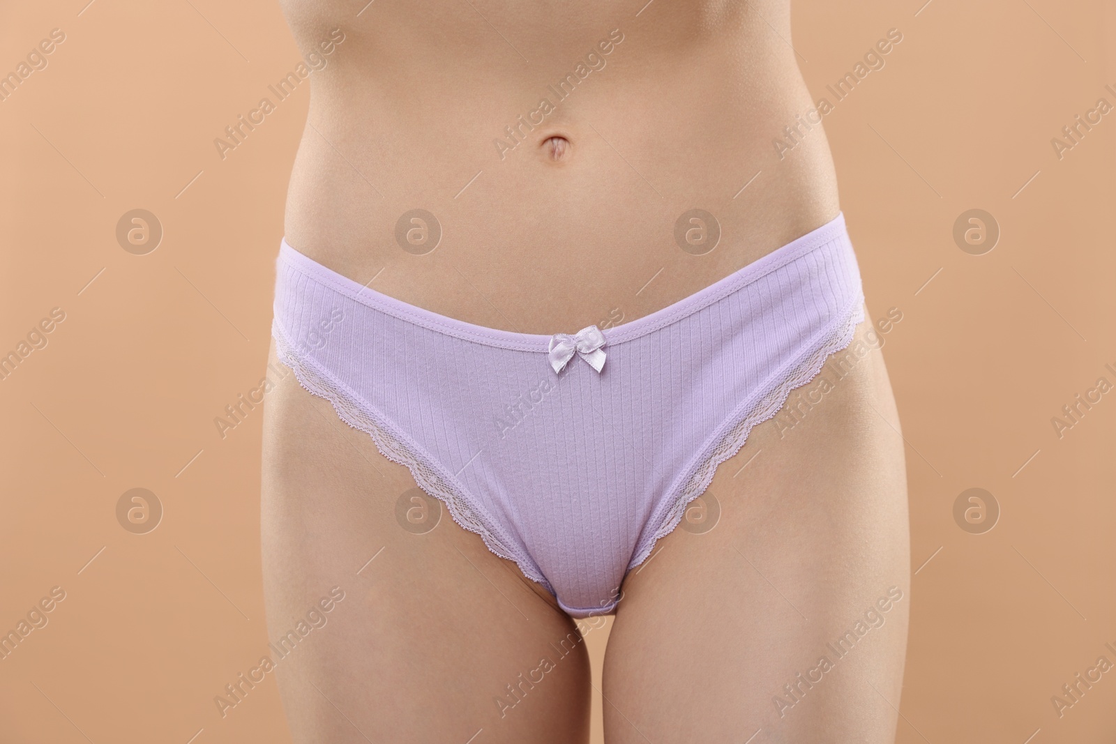 Woman wearing beautiful underwear on beige background, closeup Photo of Woman wearing beautiful underwear on beige background, closeup