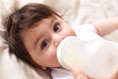 Photo of Father feeding his little baby with bottle on bed at home, closeup