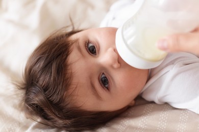 Photo of Father feeding his little baby with bottle on bed at home, closeup
