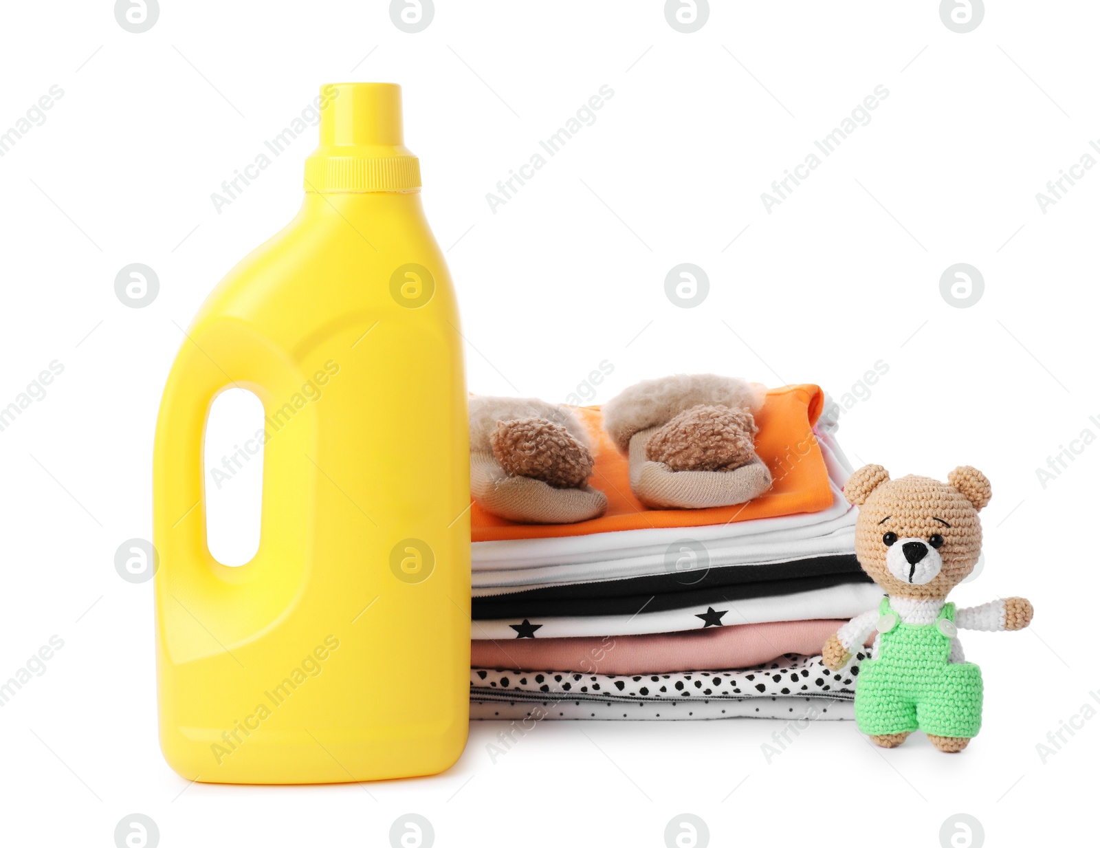 Bottle with fabric softener, shoes, baby clothes and toy isolated on white Photo of Bottle with fabric softener, shoes, baby clothes and toy isolated on white