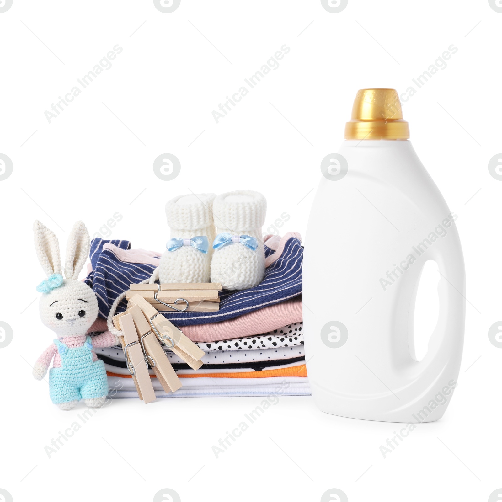 Bottle with fabric softener, shoes, baby clothes, clothespins and toy isolated on white Photo of Bottle with fabric softener, shoes, baby clothes, clothespins and toy isolated on white