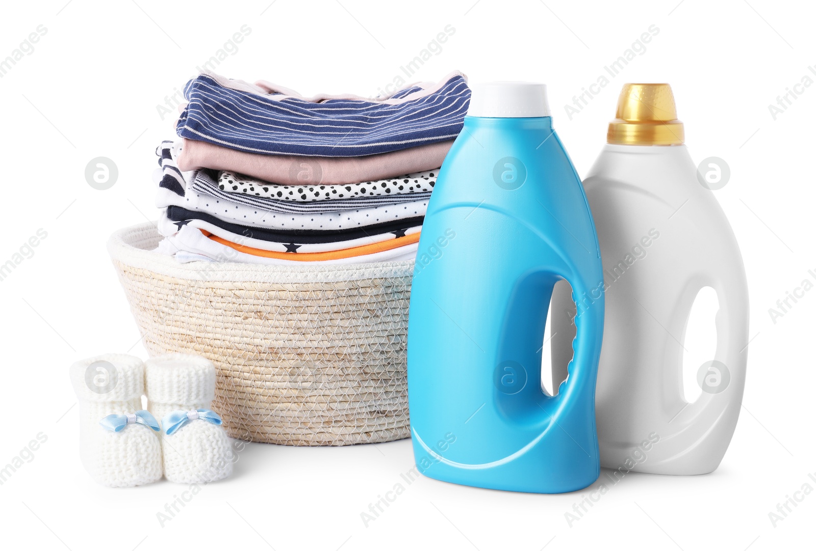 Bottles with fabric softener, shoes, basket and baby clothes isolated on white Photo of Bottles with fabric softener, shoes, basket and baby clothes isolated on white