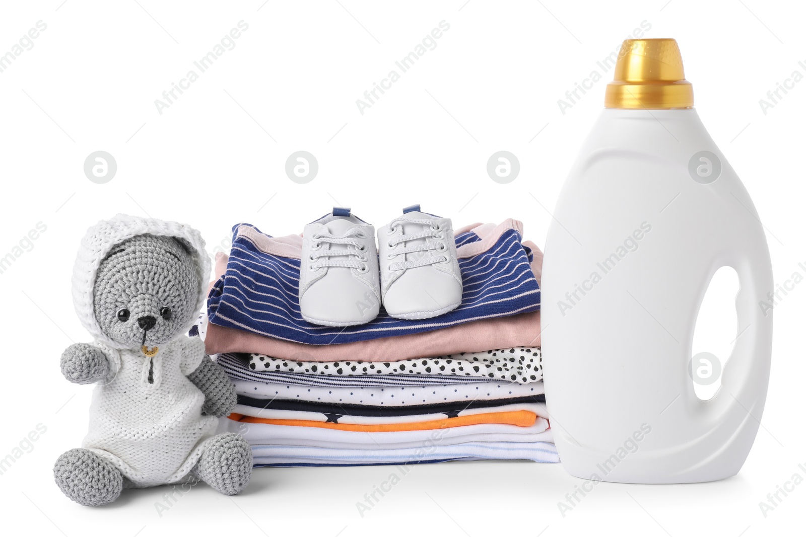 Bottle with fabric softener, shoes, baby clothes and toy isolated on white Photo of Bottle with fabric softener, shoes, baby clothes and toy isolated on white