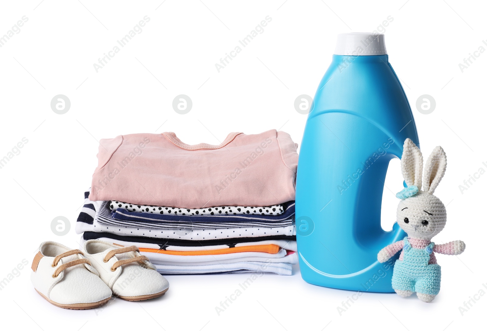 Bottle with fabric softener, shoes, baby clothes and toy isolated on white Photo of Bottle with fabric softener, shoes, baby clothes and toy isolated on white