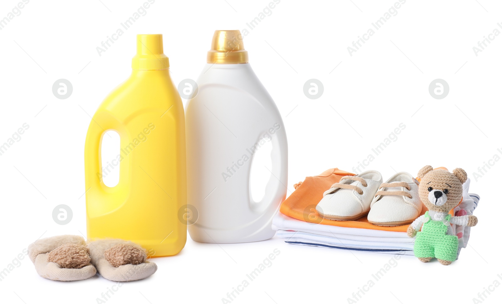 Bottles with fabric softener, shoes, baby clothes and toy isolated on white Photo of Bottles with fabric softener, shoes, baby clothes and toy isolated on white