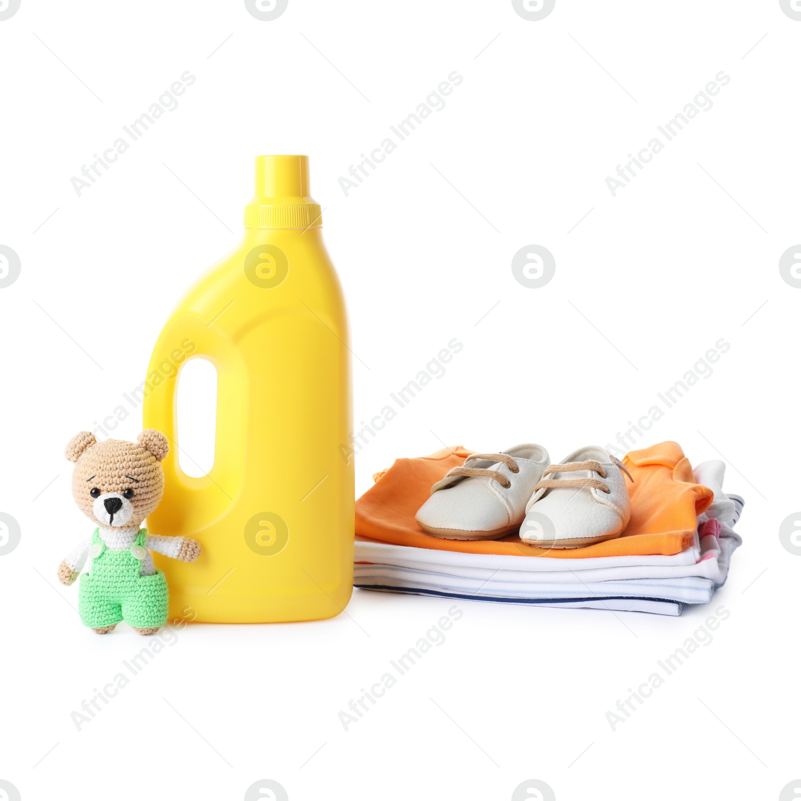 Bottle with fabric softener, shoes, baby clothes and toy isolated on white Photo of Bottle with fabric softener, shoes, baby clothes and toy isolated on white