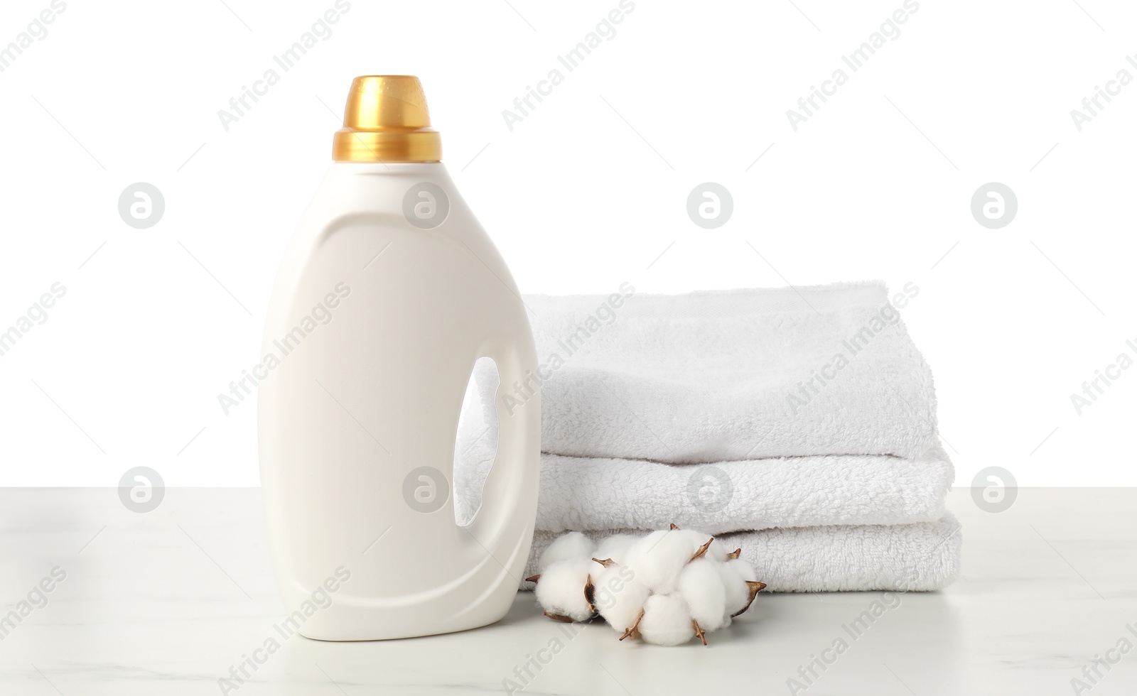 Bottle of fabric softener, stacked towels and cotton flowers on marble table against white background Photo of Bottle of fabric softener, stacked towels and cotton flowers on marble table against white background
