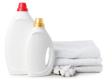 Photo of Bottles of fabric softener, stacked towels and cotton flowers isolated on white