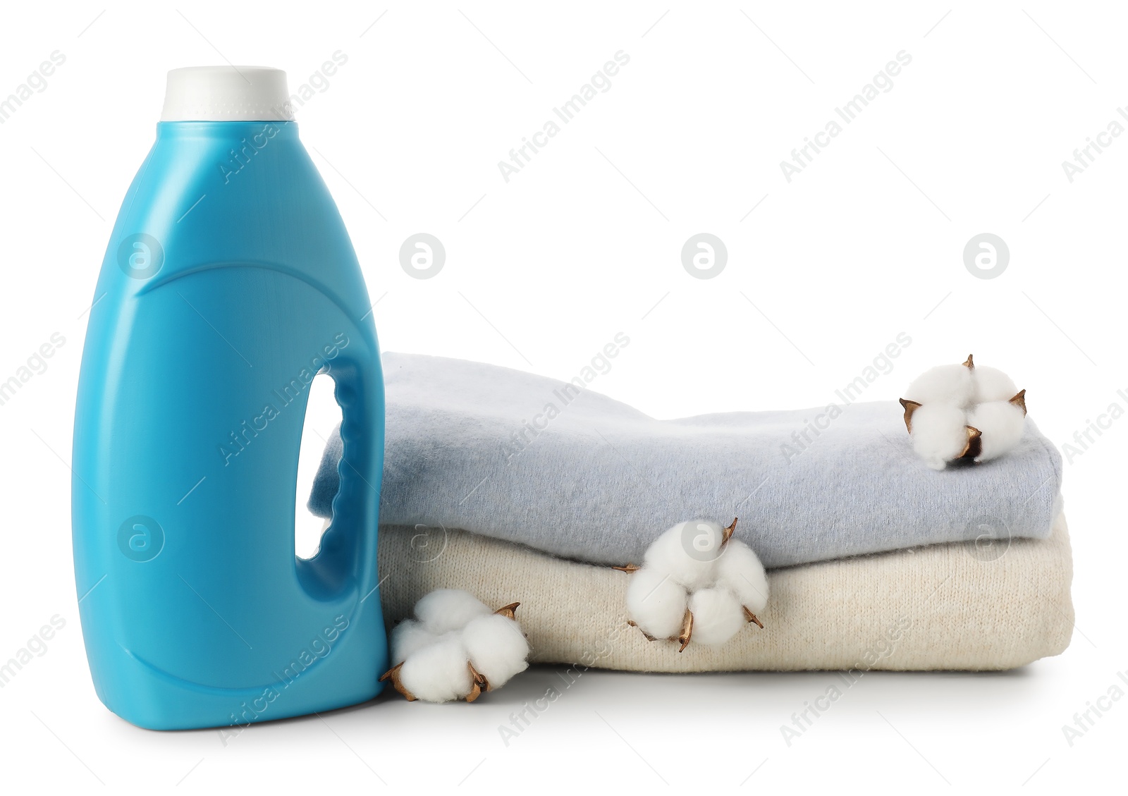 Photo of Bottle of fabric softener, stacked clothes and cotton flowers isolated on white