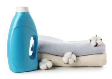 Photo of Bottle of fabric softener, stacked clothes and cotton flowers isolated on white