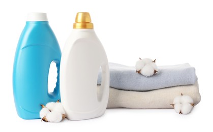 Photo of Bottles of fabric softener, stacked clothes and cotton flowers isolated on white