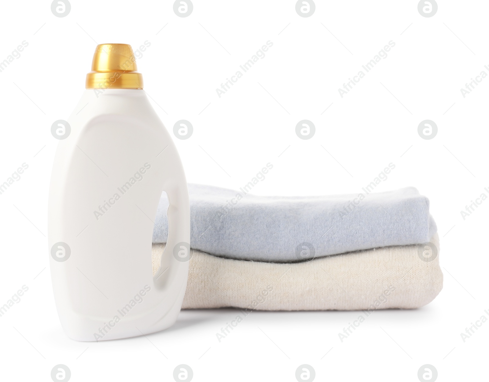 Bottle of fabric softener and stacked clothes isolated on white Photo of Bottle of fabric softener and stacked clothes isolated on white