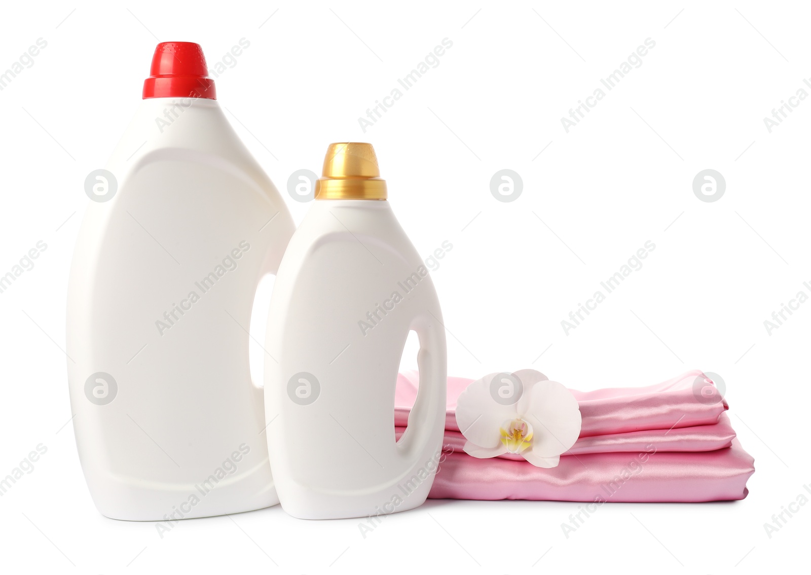 Bottles of fabric softener, stacked clothes and flower isolated on white Photo of Bottles of fabric softener, stacked clothes and flower isolated on white