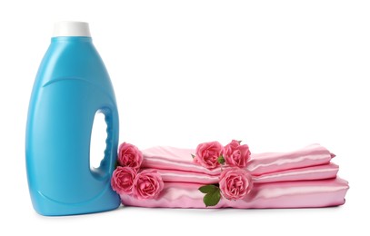 Photo of Bottle of fabric softener, stacked clothes and flowers isolated on white