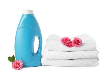 Photo of Bottle of fabric softener, stacked towels and flowers isolated on white