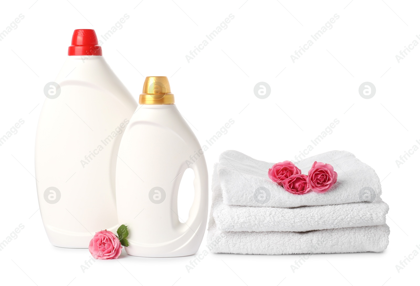Photo of Bottles of fabric softener, stacked towels and flowers isolated on white