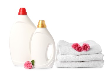 Photo of Bottles of fabric softener, stacked towels and flowers isolated on white