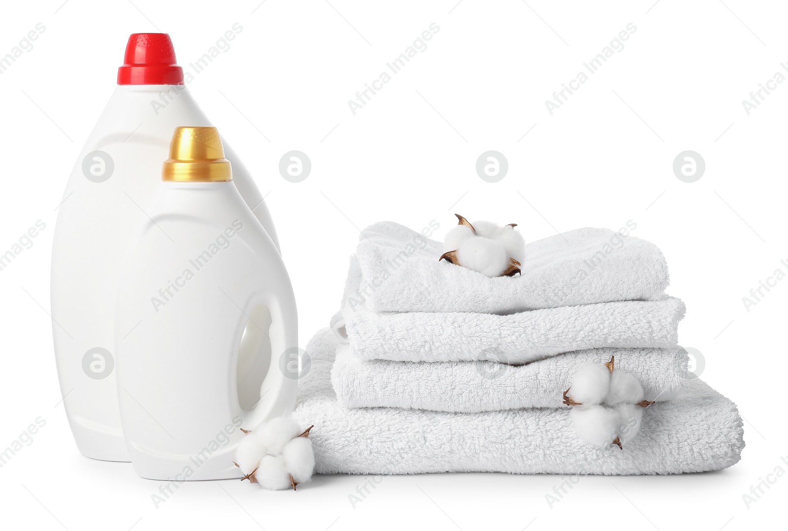 Photo of Bottles of fabric softener, stacked towels and cotton flowers isolated on white
